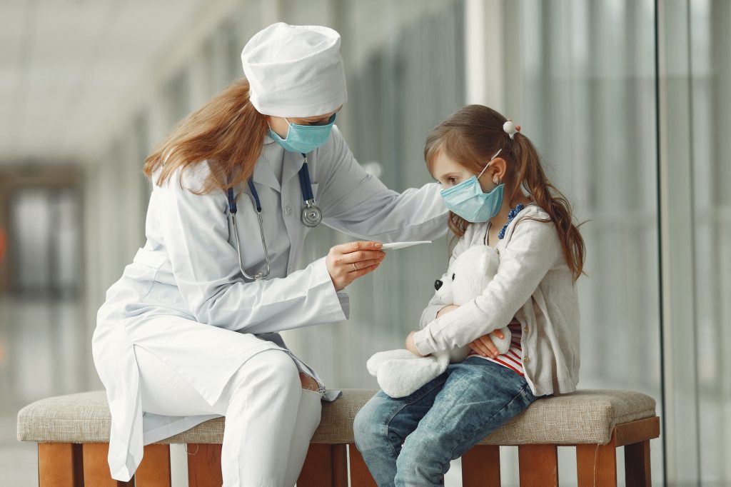 Doctor and a child in protective masks are in hospital