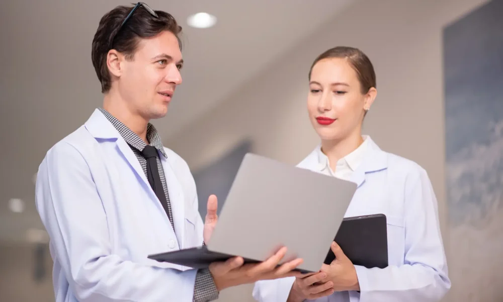 shot-of-two-young-doctors-using-a-tablet-and-havin