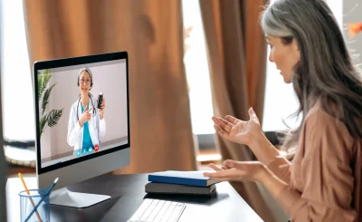 Online medical consultation.Gray-haired senior woman talks with a therapist female doctor by video call uses computer, getting medical consultation,receives answers to questions and recommendations for treatment